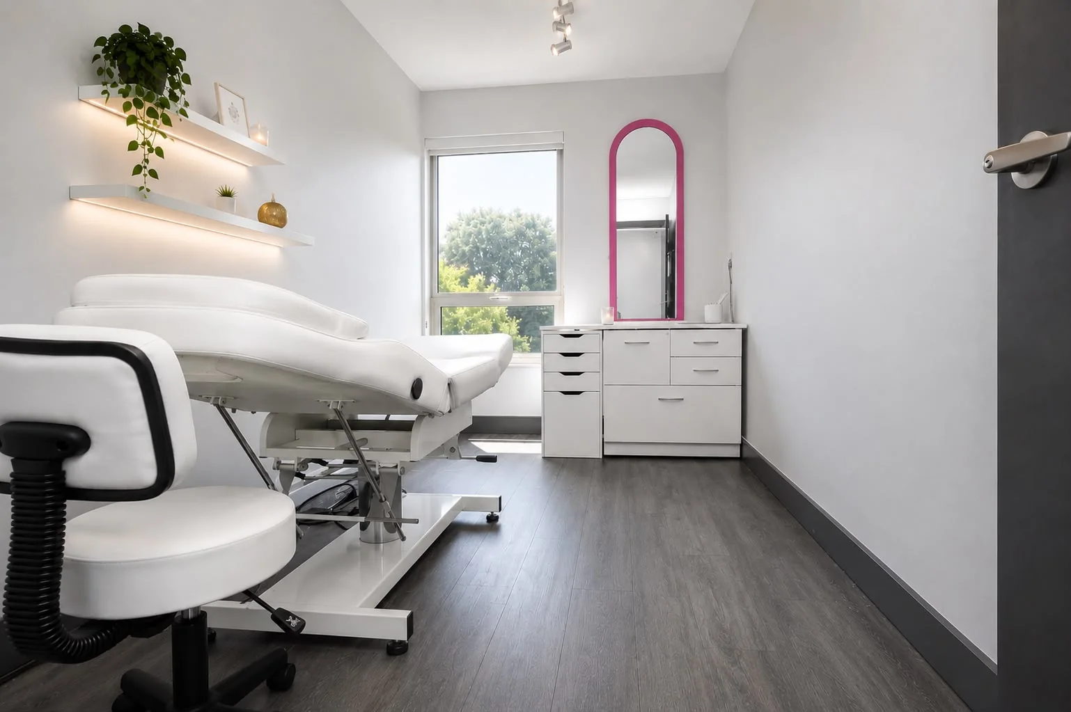 Cabine de soins privée, table blanche, miroir fuchsia et étagères lumineuses