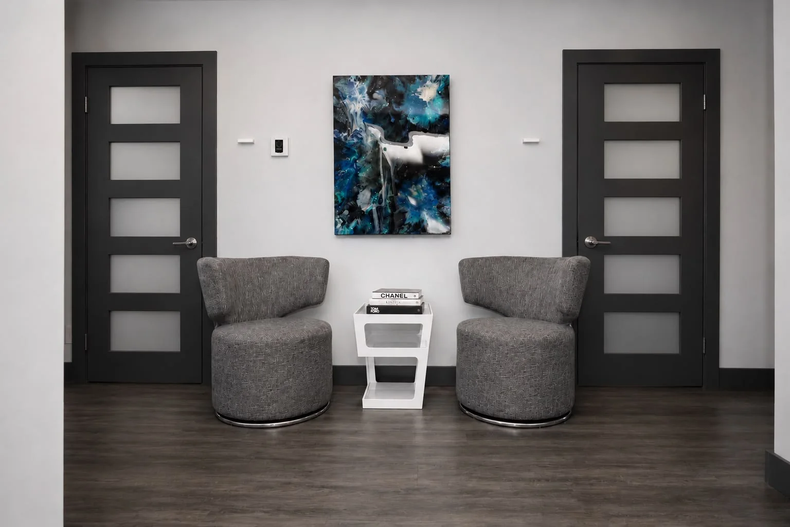 Coin d'attente avec fauteuils pivotants gris et œuvre d'art bleue