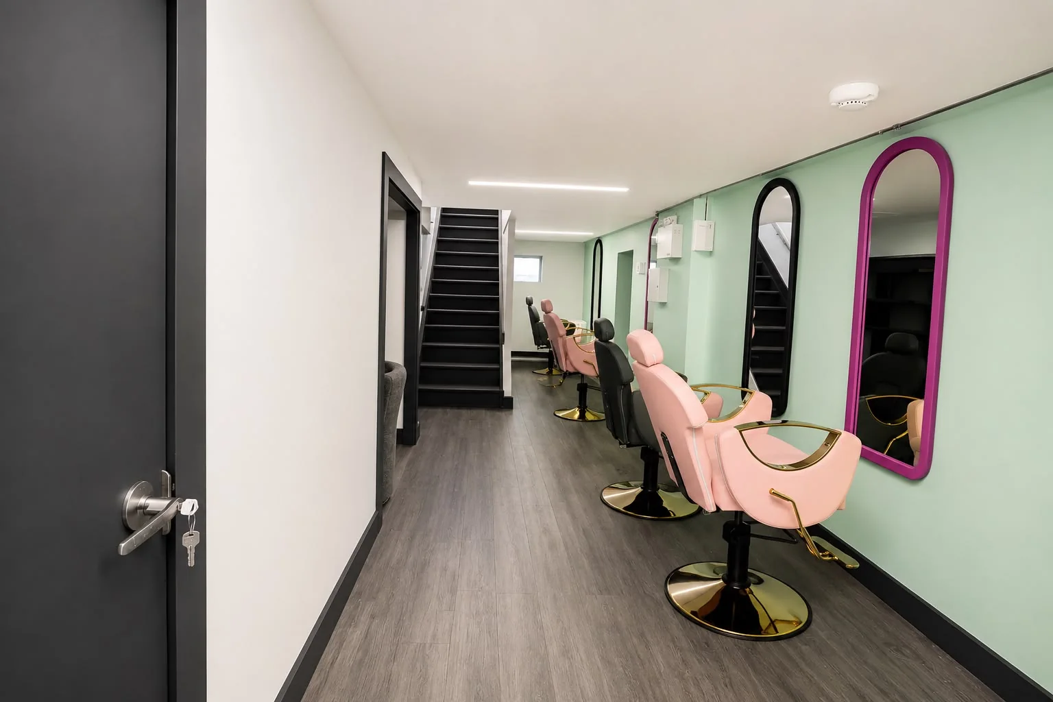 Rangée de postes de coiffage devant un mur menthe et miroirs colorés